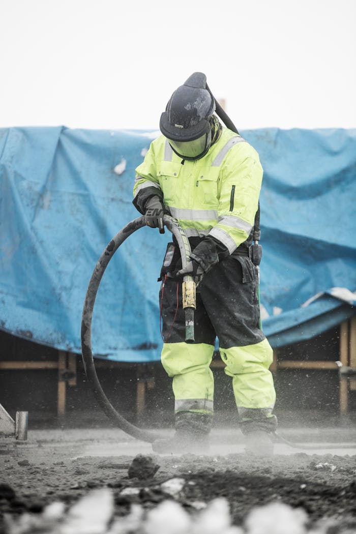 Construction worker operating heavy machinery at a building site, ensuring safety and precision.